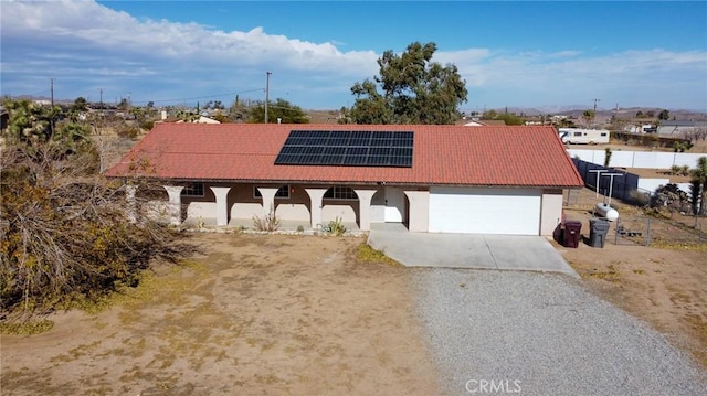 58168 Canterbury St, Yucca Valley, CA 92284 - view of front of home featuring driveway, roof mounted solar panels, stucco siding, and an attached garage