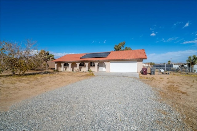 58168 Canterbury St, Yucca Valley, CA 92284 - view of front of house with stucco siding, solar panels, an attached garage, driveway, and a tile roof