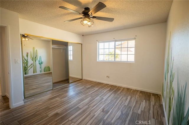 unfurnished bedroom with ceiling fan, wood-type flooring, a textured ceiling, and a closet