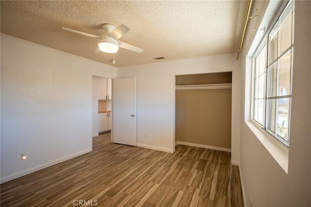 58168 Canterbury St, Yucca Valley, CA 92284 - unfurnished bedroom featuring a textured ceiling, multiple windows, wood finished floors, a closet, and ceiling fan