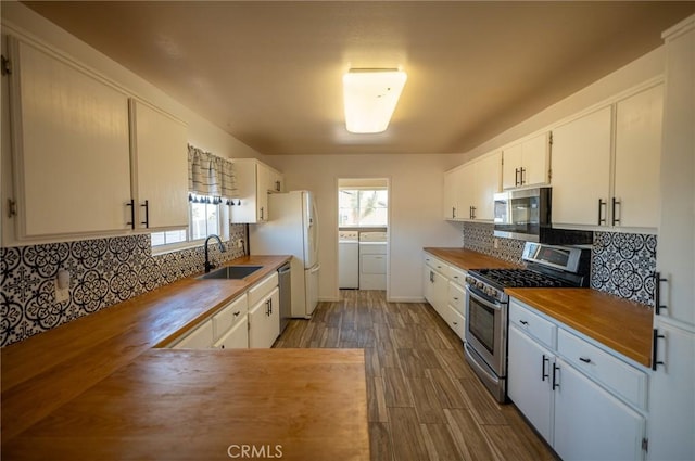 kitchen with backsplash, stainless steel appliances, washer and clothes dryer, sink, and white cabinets