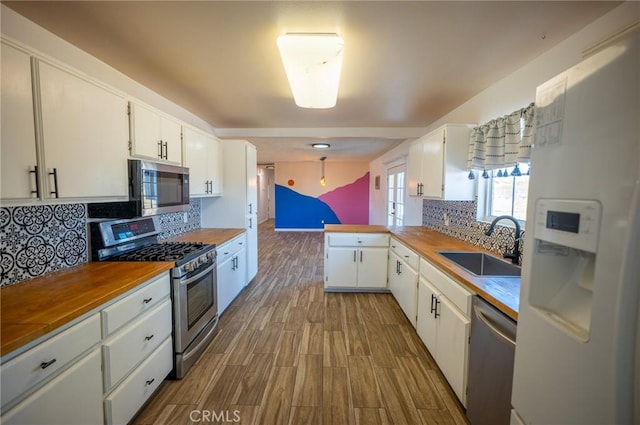58168 Canterbury St, Yucca Valley, CA 92284 - kitchen with stainless steel appliances, backsplash, white cabinets, wood finished floors, and a peninsula