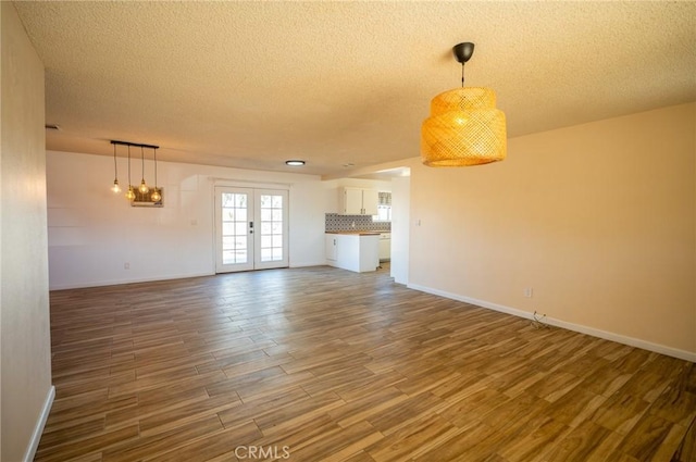 unfurnished living room featuring french doors, wood-type flooring, and a textured ceiling