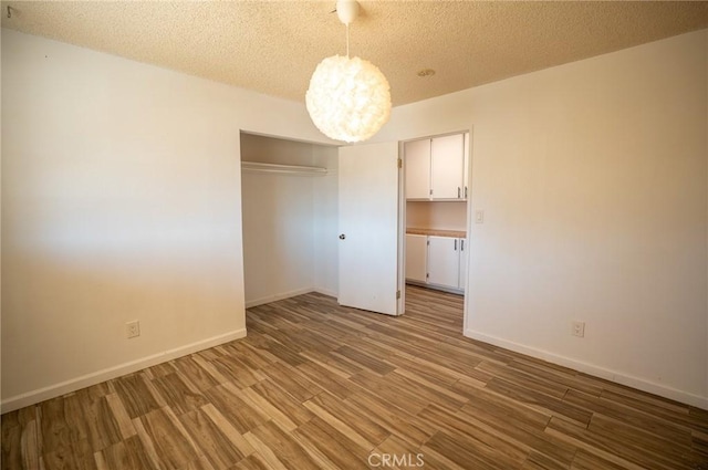 58168 Canterbury St, Yucca Valley, CA 92284 - unfurnished bedroom with wood finished floors, a chandelier, a closet, and a textured ceiling