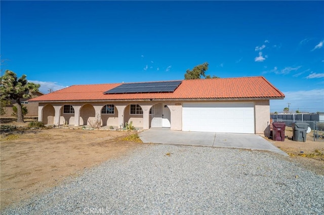 58168 Canterbury St, Yucca Valley, CA 92284 - mediterranean / spanish-style house with driveway, stucco siding, roof mounted solar panels, an attached garage, and a tile roof