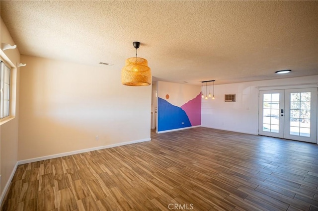 unfurnished room featuring hardwood / wood-style floors, a textured ceiling, and french doors