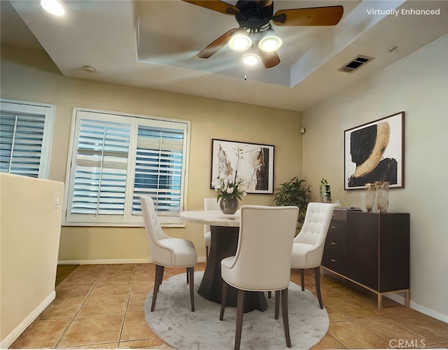 tiled dining area with a raised ceiling and ceiling fan