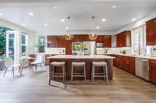 kitchen featuring sink, hanging light fixtures, hardwood / wood-style flooring, a kitchen island, and stainless steel appliances