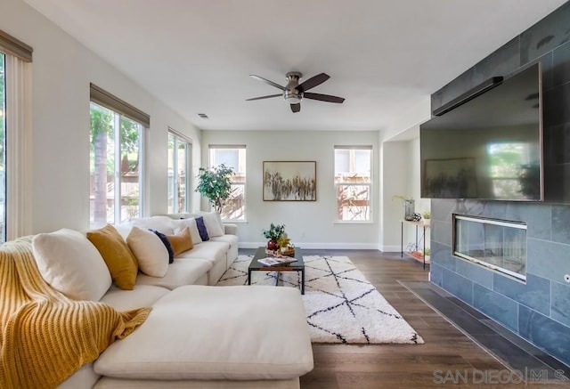 living room with a tile fireplace, ceiling fan, and dark hardwood / wood-style flooring