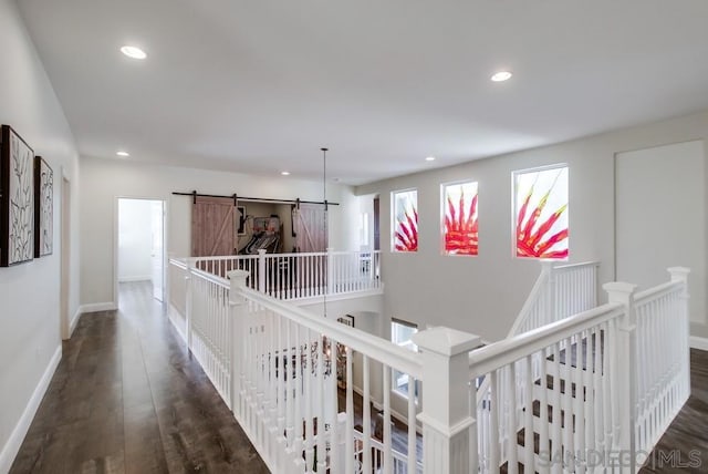 corridor featuring a barn door and dark hardwood / wood-style flooring