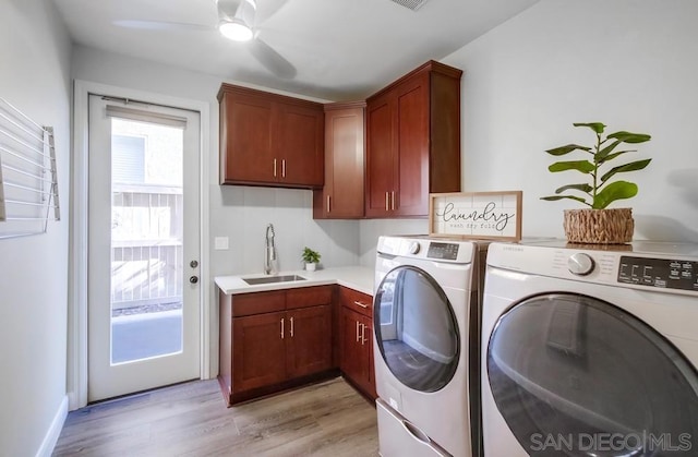 laundry area featuring washer and clothes dryer, light hardwood / wood-style floors, cabinets, and sink