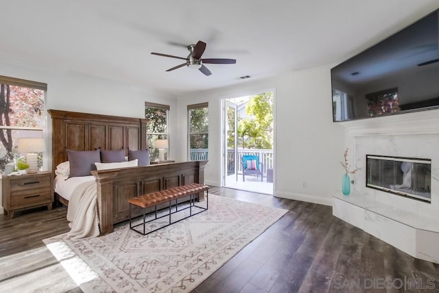 bedroom with ceiling fan, dark hardwood / wood-style flooring, a premium fireplace, and access to outside