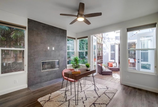 sunroom with ceiling fan and a tiled fireplace