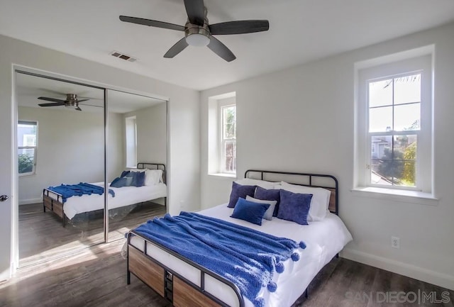 bedroom with multiple windows, ceiling fan, a closet, and dark wood-type flooring