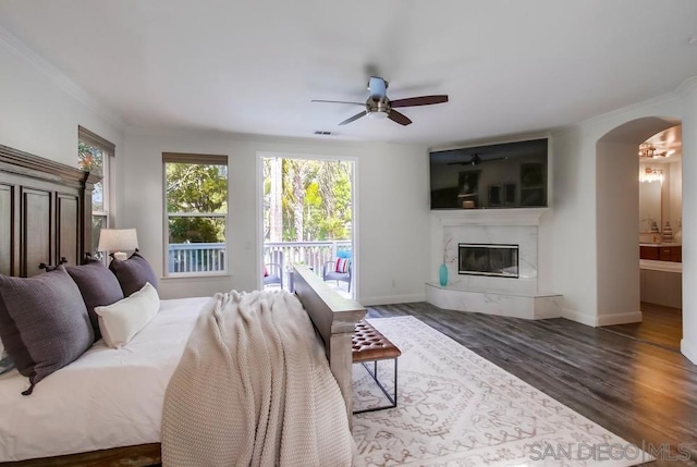 bedroom with access to exterior, dark hardwood / wood-style flooring, ensuite bathroom, ceiling fan, and a premium fireplace