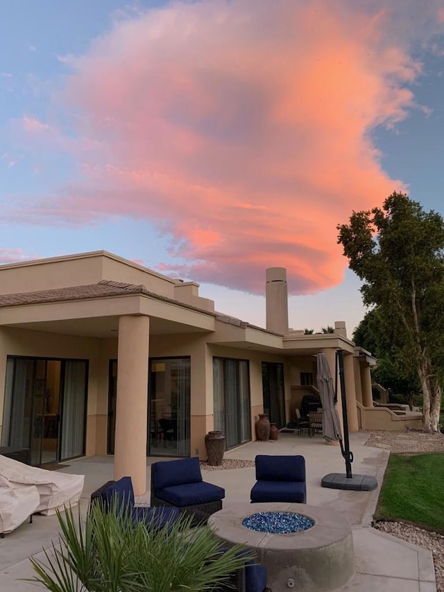 back house at dusk with an outdoor fire pit and a patio area