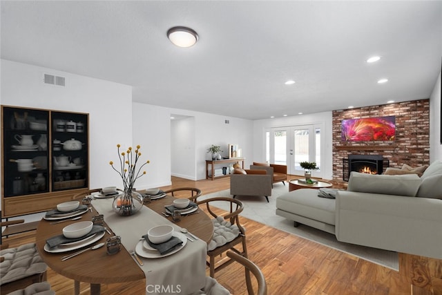 interior space with french doors, a brick fireplace, and light hardwood / wood-style floors