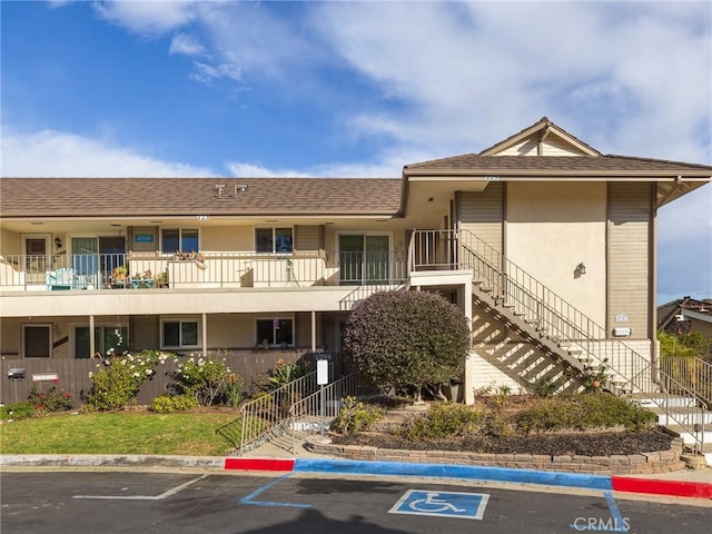 view of property with stairs and uncovered parking