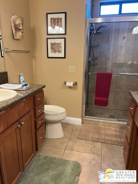 bathroom with toilet, vanity, tile patterned floors, and a shower with door