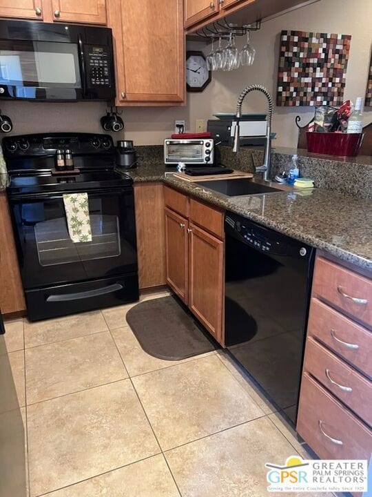 kitchen with black appliances, light tile patterned floors, sink, and dark stone counters