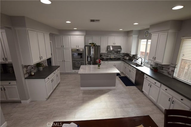 kitchen with appliances with stainless steel finishes, white cabinets, a center island, and sink