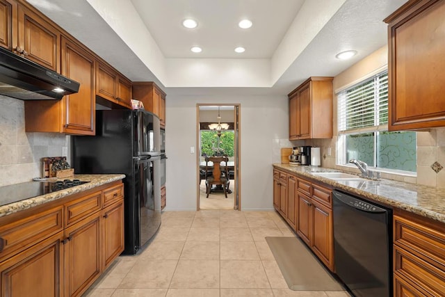 kitchen with light stone countertops, sink, tasteful backsplash, and black appliances