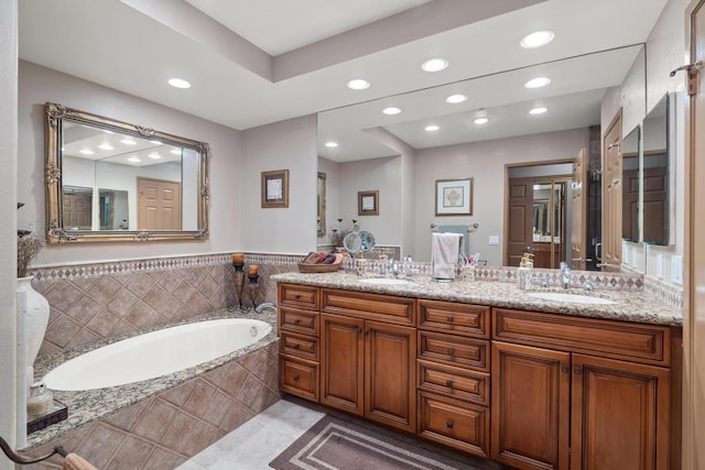 bathroom featuring tile patterned flooring, vanity, and tiled bath