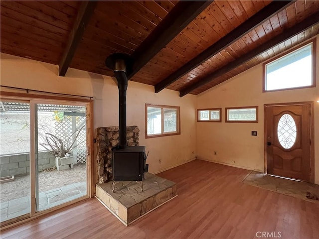 entrance foyer with lofted ceiling with beams, a wood stove, and a wealth of natural light