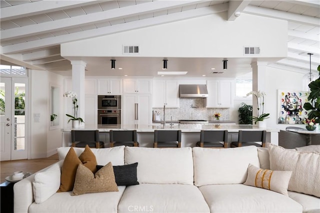 living room featuring wood-type flooring, lofted ceiling with beams, and sink