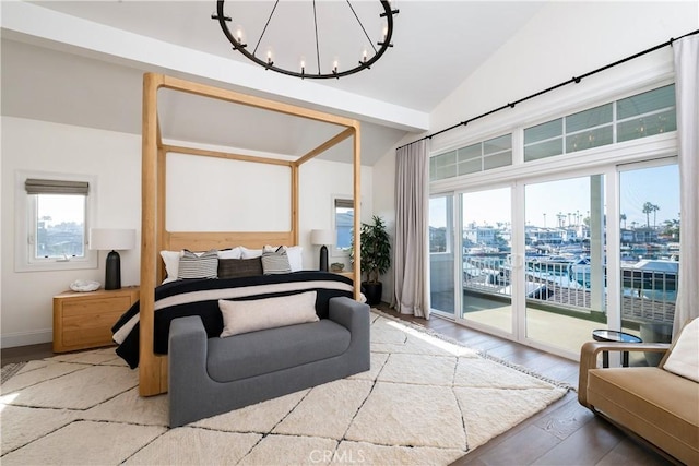 bedroom featuring hardwood / wood-style flooring, vaulted ceiling, multiple windows, and an inviting chandelier