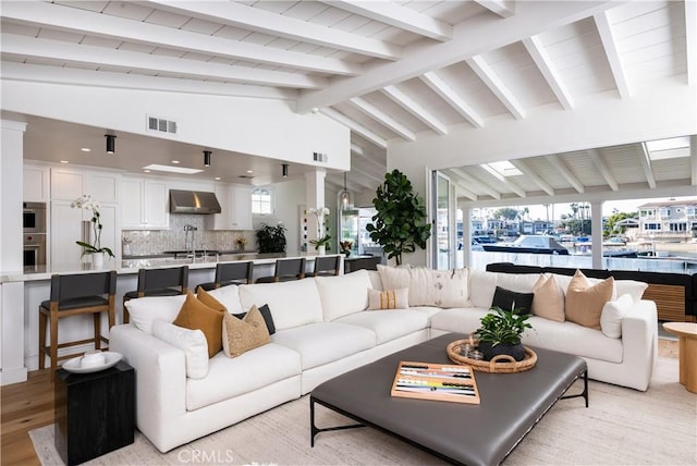 living room featuring vaulted ceiling with beams and light hardwood / wood-style floors