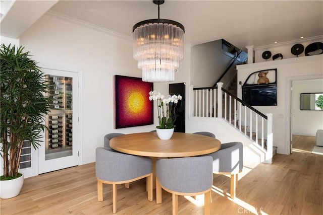 dining space with light hardwood / wood-style floors, ornamental molding, and a chandelier