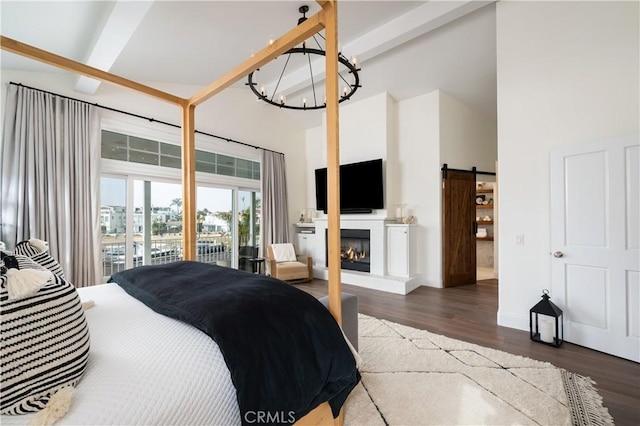 bedroom featuring beamed ceiling, a barn door, dark wood-type flooring, and a high ceiling