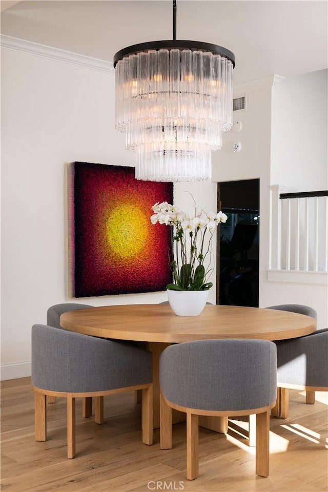 dining area featuring hardwood / wood-style floors, ornamental molding, and an inviting chandelier