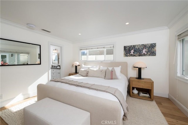 bedroom with light wood-type flooring, ensuite bathroom, and ornamental molding