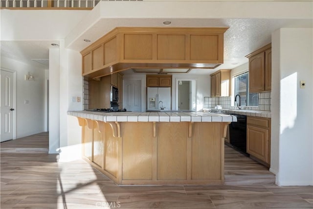 kitchen featuring tile countertops, tasteful backsplash, white fridge with ice dispenser, and dishwasher