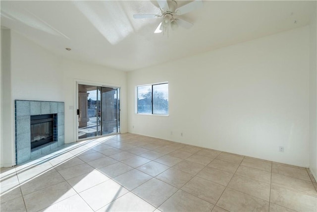 unfurnished living room featuring a tiled fireplace, tile patterned floors, and a ceiling fan