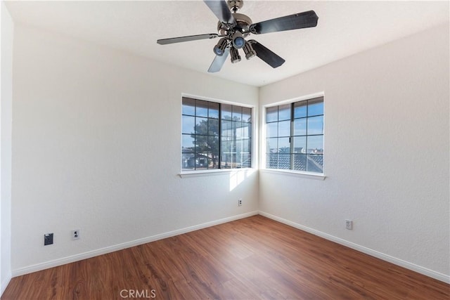 spare room featuring ceiling fan, baseboards, and wood finished floors