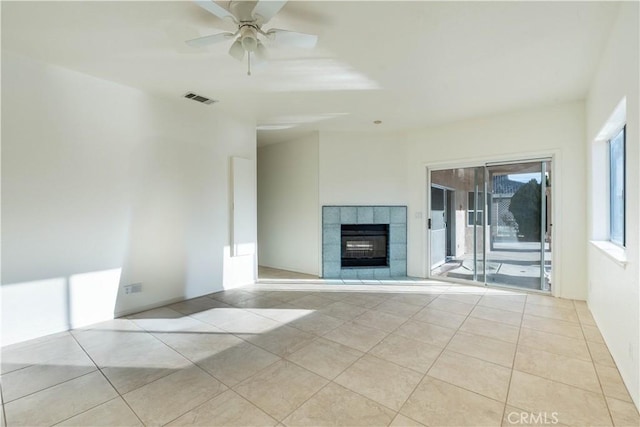 unfurnished living room featuring tile patterned floors, a fireplace, visible vents, and ceiling fan