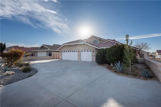 view of front of home featuring stucco siding, an attached garage, driveway, and fence