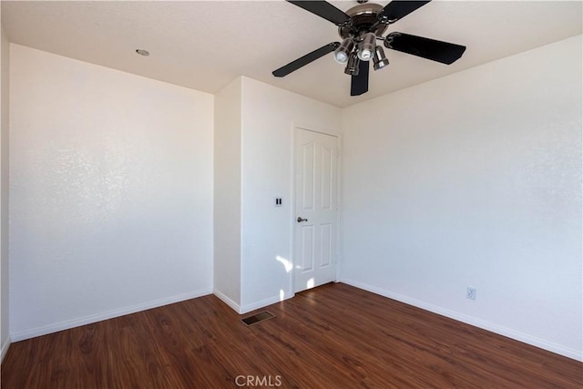 spare room with visible vents, baseboards, dark wood-style flooring, and ceiling fan