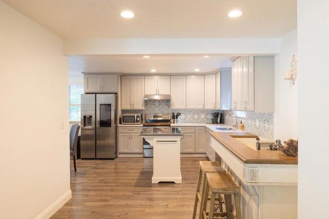 kitchen with sink, a breakfast bar area, white cabinets, kitchen peninsula, and stainless steel appliances