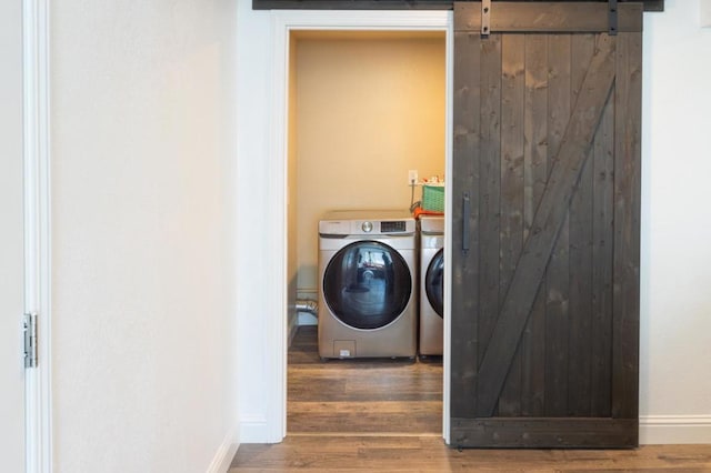 laundry room featuring wood-type flooring, a barn door, and washer and dryer