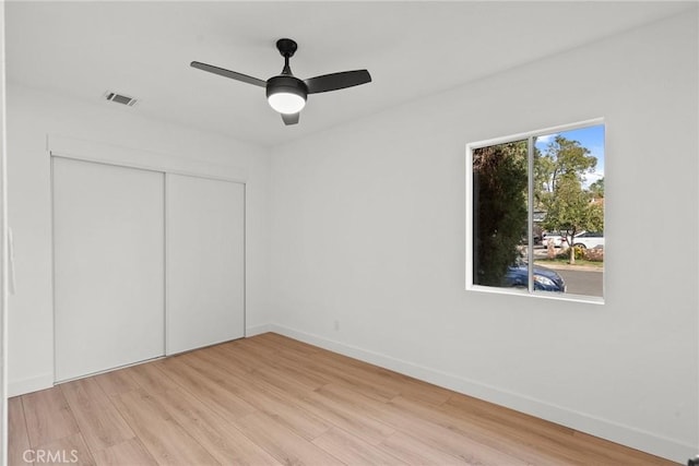 unfurnished bedroom featuring ceiling fan, light wood-type flooring, and a closet