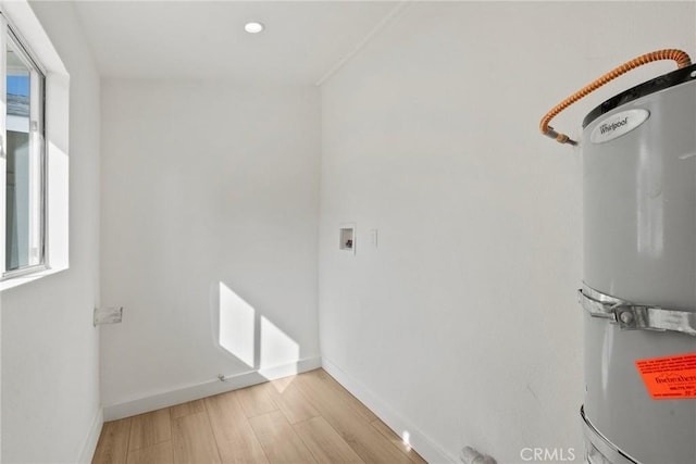 interior space with hookup for a washing machine, strapped water heater, and light hardwood / wood-style floors