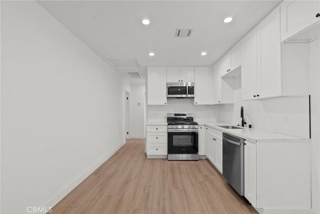 kitchen with white cabinets, stainless steel appliances, light hardwood / wood-style flooring, and sink