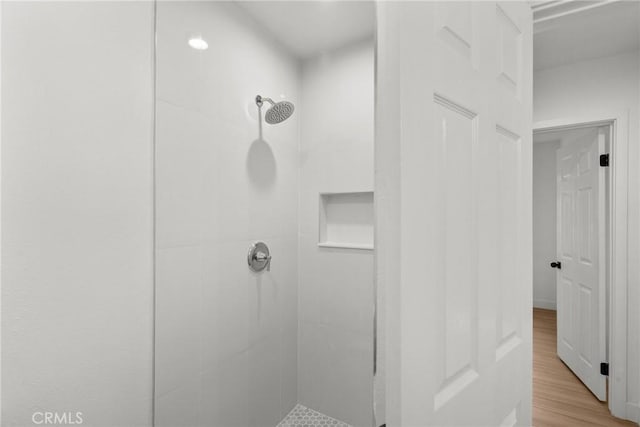 bathroom with tiled shower and hardwood / wood-style flooring