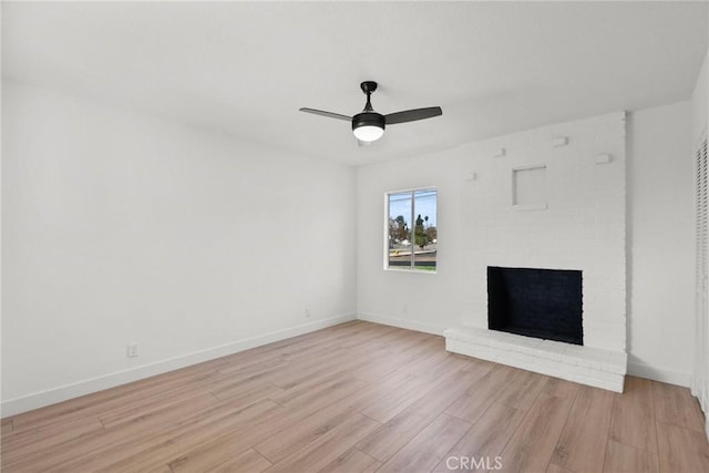 unfurnished living room with light wood-type flooring, a brick fireplace, and ceiling fan