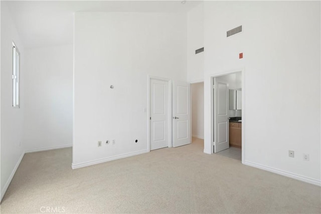 unfurnished room with a towering ceiling and light carpet