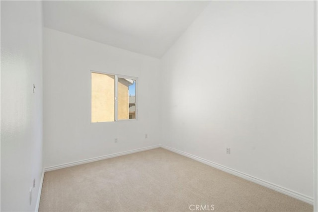 carpeted spare room with vaulted ceiling